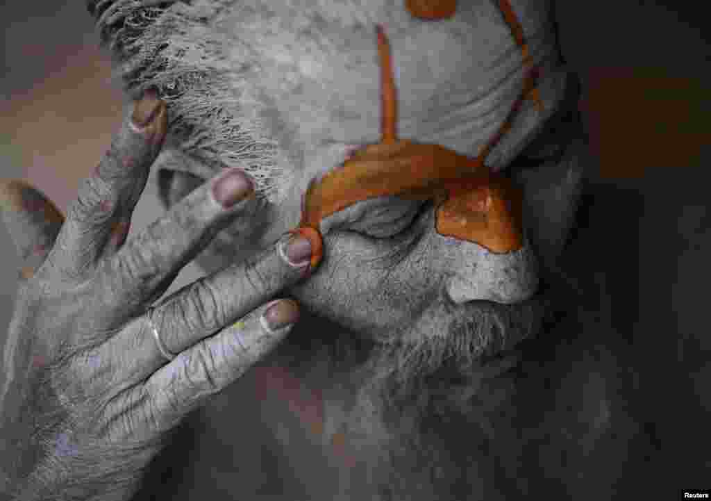 A Hindu sadhu (holy man) applies paint to his forehead at his ashram on the premises of Pashupatinath Temple in Kathmandu, Nepal. Hindu holy men from Nepal and India come to the temple to take part in the Shivaratri festival, which this year falls on March 10.