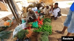 FILE: Customers look on as a vender displays fresh produce in Khartoum, Sudan. Taken Dec. 2, 2016.