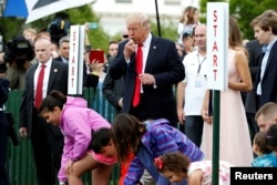 U.S. President Donald Trump blows a whistle to start the White House Easter Egg Roll alongside first lady Melania Trump and his son Barron, right, on the South Lawn of the White House in Washington, April 17, 2017.