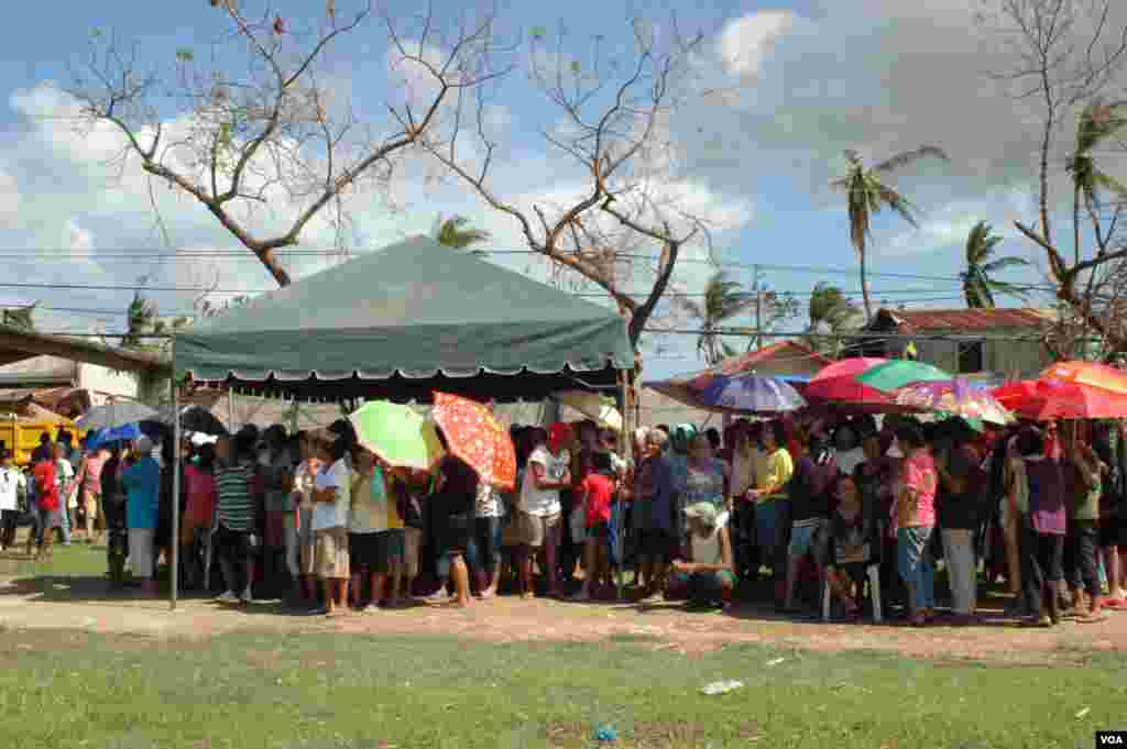 A group of people, mostly seniors, waits for relief supplies in the blazing sun, Cebu, Philippines, Nov. 15, 2013. (Steve Herman/VOA)