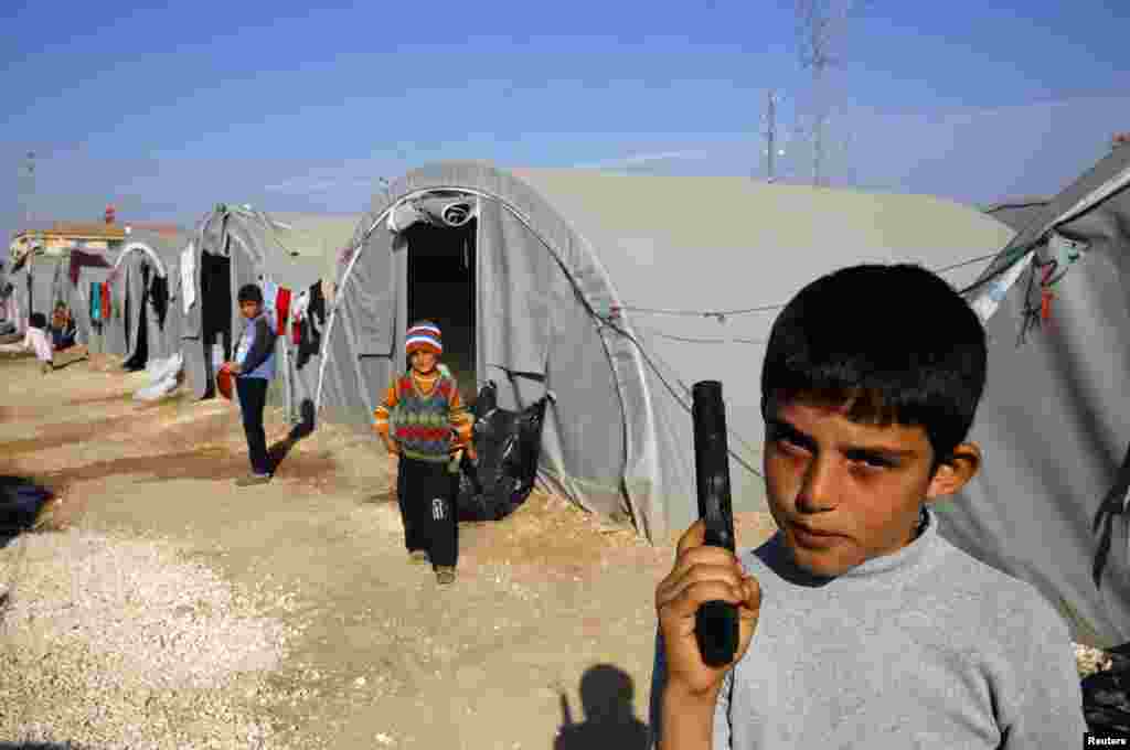 A young refugee from Kobani holds a toy pistol at a Kurdish refugee camp in the border town of Suruc, Turkey, Oct. 27, 2014.