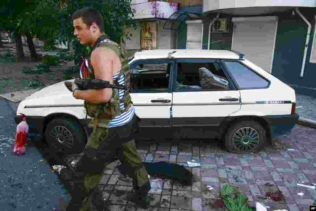 A Pro-Russian rebel passes by a car which was hit by shrapnel from a shell in the town of Donetsk, eastern Ukraine, Aug. 27, 2014.&nbsp;