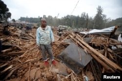 FILE - A man stands on the rubbles of his home after bulldozers demolished dozens of houses to make way for a new road in the Kibera slum in Nairobi, Kenya, July 23, 2018.