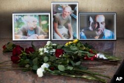 FILE - Flowers are placed by portraits of slain journalists Alexander Rastorguyev, Kirill Radchenko and Orkhan Dzhemal, at the Russian Journalists Union building in Moscow, Russia, Wednesday, Aug. 1, 2018.