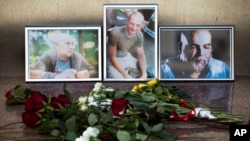 Flowers are placed by portraits of slain journalists Alexander Rastorguyev, Kirill Radchenko and Orkhan Dzhemal, at the Russian journalists Union building in Moscow, Russia, Wednesday, Aug. 1, 2018.