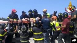 FILE - Eleven-year-old Ciro is carried on a stretcher after being rescued by Italian firefighters from the rubble of a collapsed building in Casamicciola, on the island of Ischia, near Naples, Italy, Aug. 22, 2017, a day after a 4.0-magnitude quake hit.