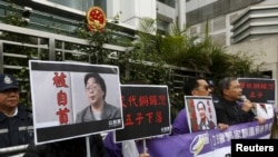 资料照：香港抗议者在北京驻香港机构中联办前手举铜锣湾书店失踪老板桂民海的照片。 （2016年1月19日）