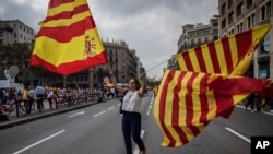 Seorang perempuan mengibarkan bendera Catalonia dan Spanyol pada liburan "Dia de la Hispanidad" atau Hari Nasional Spanyol di Barcelona, Spanyol, 12 Oktober 2017. (Foto: dok).
