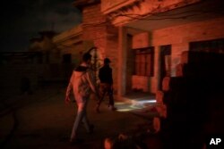In this April 2, 2019 photo, an Iraqi army 20th division soldier walks with a civilian during a nighttime raid near Badoush, Iraq. The small town on the banks of the Tigris River was once one of the Islamic State group's most diehard strongholds.