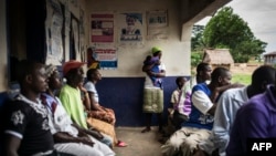 Une mère porte dans ses bras son bébé, nouveau-né, à côté d’autres malades, dans un centre de santé, dans le village libérien de Mendicorma, à Sierra Leone, 27 avril 2016. 