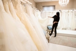 FILE - Anita Galafate checks wedding dresses in a shop in Rome, Tuesday, March 9, 2021. Couples in the U.S. are racing to the altar amid a vaccination-era wedding boom that has venues and other vendors in high demand. (AP Photo/Alessandra Tarantino, File