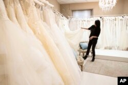 FILE - Anita Galafate checks wedding dresses in a shop in Rome, Tuesday, March 9, 2021. Couples in the U.S. are racing to the altar amid a vaccination-era wedding boom that has venues and other vendors in high demand. (AP Photo/Alessandra Tarantino, File