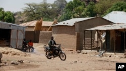 FILE - An unidentified man rides a motorbike past houses in Chibok, Nigeria, May 19, 2014. Boko Haram fighters have returned to the area according to local leaders.