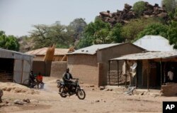 FILE - An unidentified man rides a motorbike past houses in Chibok, Nigeria, May 19, 2014. Boko Haram fighters have returned to the area, according to local leaders.