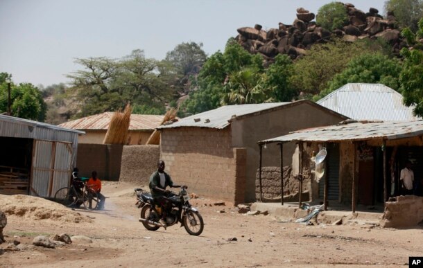 FILE - An unidentified man rides a motorbike past houses in Chibok, Nigeria, May 19, 2014. Boko Haram fighters have returned to the area, according to local leaders.