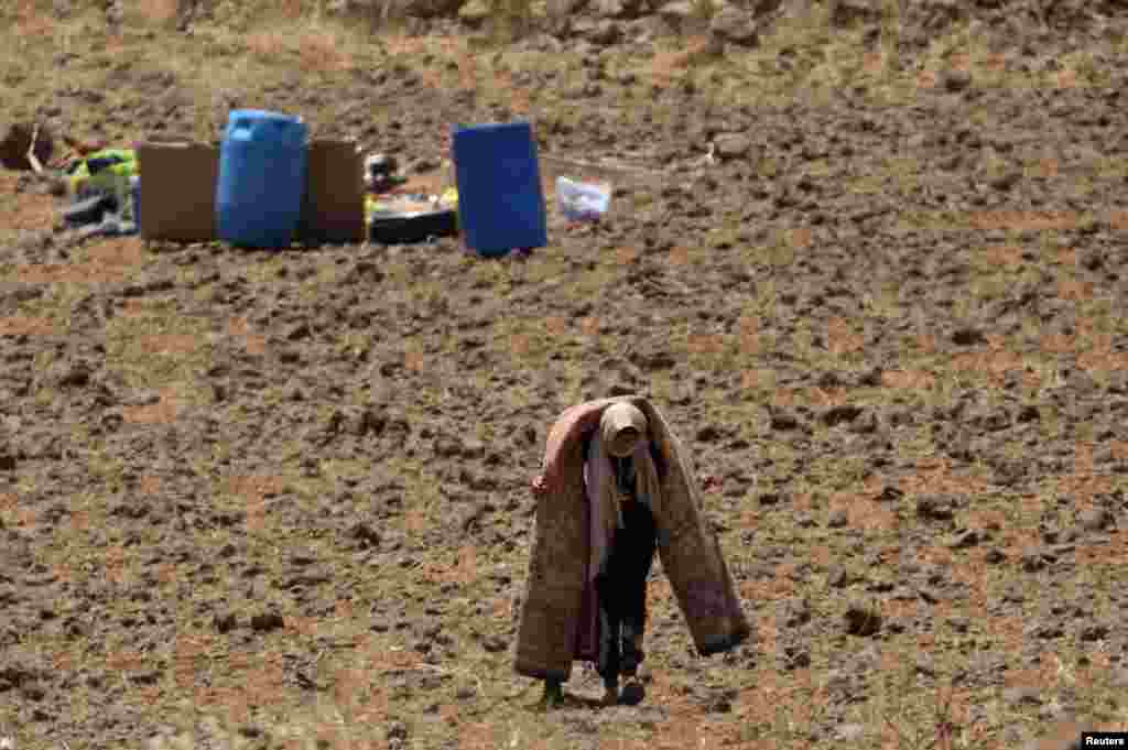 A woman carries a carpet near the Israeli-occupied Golan Heights in Quneitra, Syria, July 2, 2018.
