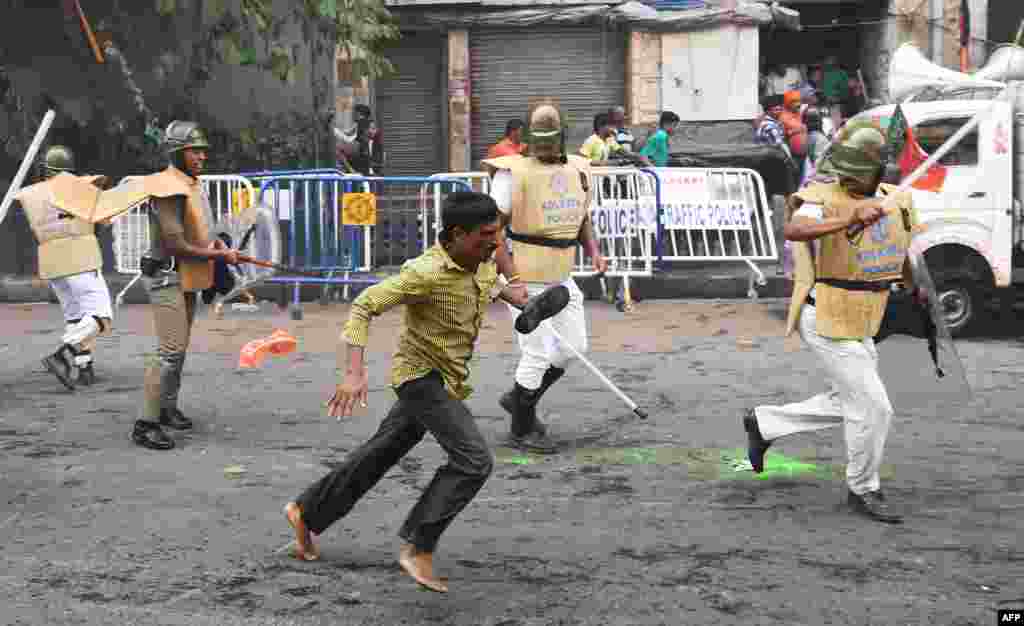 کولکتہ میں بھارتہ جنتا پارٹی&nbsp; (BJP) کا ایک کارکن دوڑتے ہوئے بھارتی پولیس کے قریب سے گزر رہا ہے۔ بی جے پی کے کارکن اپنے ایک ساتھی پر پولیس تشدد کے خلاف احتجاج کر رہے ہیں۔