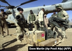 U.S. Marines load equipment and munitions aboard a CH-53 Sea Stallion helicopter at Camp Rhino in southern Afghanistan on December 10, 2001. (Dave Martin/AP)