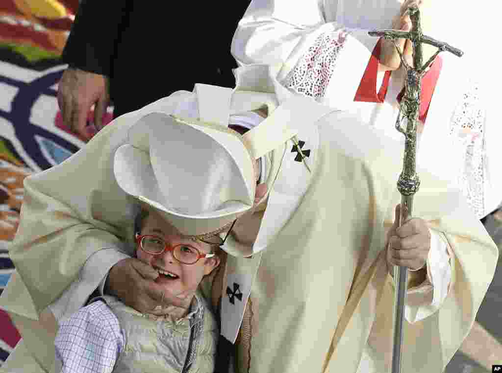 Paus Fransiskus menyapa seorang anak ketika menjalani prosesi di Basilika Guadalupe sebelum Misa di Mexico City, 13 Februari 2016.