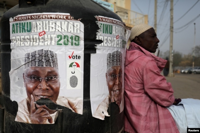 FILE PHOTO: A man sits next to a campaign poster of Atiku Abubakar, leader of the People's Democratic Party, days before the presidential election in Kano, Nigeria, Feb. 17, 2019.