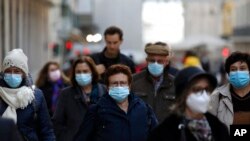 Personas con cubrebocas por el COVID-19 caminan por una calle del centro de Lisboa, Portugal, el 29 de noviembre de 2021.