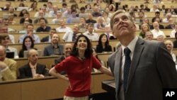 Fabiola Gianotti, Atlas team spokeswoman, and Joe Incandela, from the CMS team, look at a screen Wednesday during a scientific seminar to deliver the latest update in the search for the Higgs boson