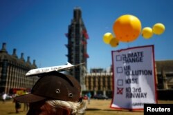 Protesters unfurl a banner against the expansion of Heathrow airport opposite the Houses of Parliament in London, Britain, June 25, 2018.