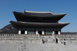 A visitor wearing a face mask poses for a photo at the Gyeongbok Palace, one of South Korea's well-known landmarks, in Seoul, South Korea, Monday, March 16, 2020.