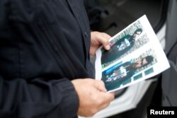 FILE - A German policeman holds the picture of a terrorist-subject infront of the main terminal of Berlin-Schoenefeld airport, in Schoenefeld, near Berlin, Oct. 9, 2016, following a suspicion that a bomb attack was being planned in Germany.