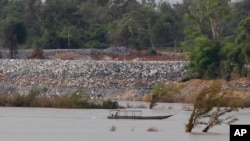 FILE - In this June 20, 2016 file photo, a fishing boat passes near a construction site of the Don Sahong dam, near Cambodia-Laos borders, in Preah Romkel village, Stung Treng province, northeast of Phnom Penh, Cambodia. 