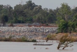 FILE - In this June 20, 2016 file photo, a fishing boat passes near a construction site of the Don Sahong dam, near Cambodia-Laos borders, in Preah Romkel village, Stung Treng province, northeast of Phnom Penh, Cambodia.