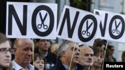 Demonstrators hold banners during a protest by trade unions against cuts in public universities in Madrid, October 23, 2012.