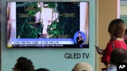 Жители Сеула (Южная Корея) смотрят телерепортаж о ракетном полигоне Сохэ в КНДР, 24 июля 2018 года