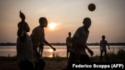 Des jeunes garçons jouent au football sur le port de Dongo, un petit village situé au bord de la rivière Ubangui, dans la région nord-ouest de la RDC, le 24 juin 2015.