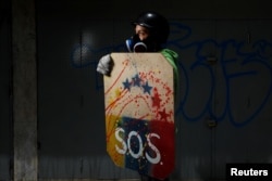 A demonstrator holding a rudimentary shield poses for a picture before a rally against Venezuelan President Nicolas Maduro's government in Caracas, Venezuela, May 27, 2017. He said: "I protest for freedom ... This regime has robbed us of everything."