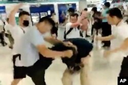 In this image taken from a July 21, 2019 video footage run by The Stand News via AP Video, white shirted men attacked a man dressed in black shirt at a subway station in Hong Kong