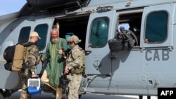 Sjaak Rijke descend de l'hélicoptère soutenu par deux soldats des forces spéciales françaises dans une base aérienne militaire française au Mali, le 6 Avril 2015. (ECPAD, photo de document)