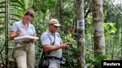 Cristina Tingle and Carlos Valderrama of WebConserva Foundation check a camera trap installed in a field in San Lucas, Colombia February 26, 2020. (REUTERS/Oliver Griffin)