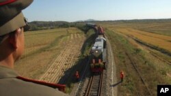 FILE - A member of the North Korean military looks at a train with Russian workers, who are going to help in the reconstruction of the Rajin-Khasan Railway. South Korea will halt the trilateral project to develop a train system to transport Russian Siberian coal to North Korea’s port in Hassan and then to South Korea by ship.