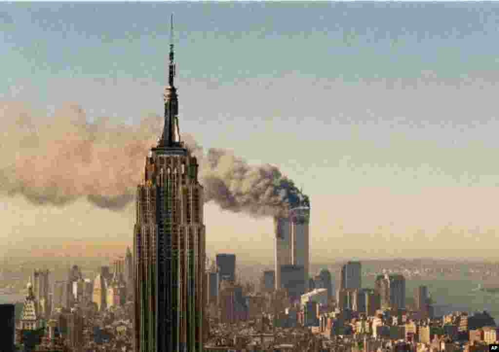 The twin towers of the World Trade Center burn behind the Empire State Building in New York, Tuesday, Sept. 11, 2001. In a horrific sequence of destruction, terrorists crashed two planes into the World Trade Center and the twin 110-story towers collapsed.