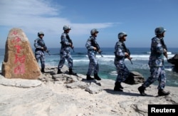 中國海軍軍人2016年1月29日在帕拉塞爾群島（中方稱西沙群島）的伍迪島（中方稱永興島）巡邏。岩石上的文字是“西沙老龍頭”，這是該島附近一堆岩石的名稱。
