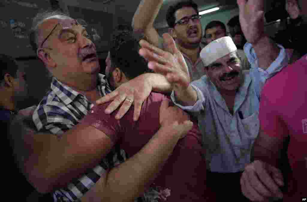 Palestinians mourn their relative in the morgue of the Shifa hospital in Gaza City on July 12, 2014.