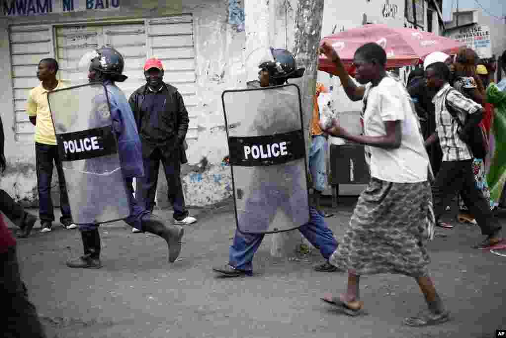 Congolese policeman in riot gear keeps an eye on Goma residents, including street children, who gathered for an anti-Kabila demonstration supported by the M23 rebel movement in Goma, DRC, November 28, 2012.