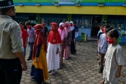 Siswa SD memakai masker, mendengarkan keterangan dari anggota tim siaga darurat (Tagana) saat program mitigasi penanggulangan virus Covid-19 di Banda Aceh, 19 November 2020.
