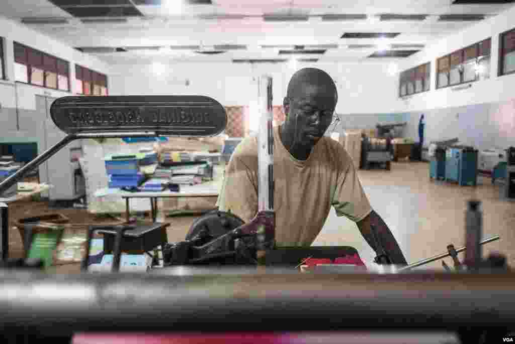 A worker is seen printing on outdated equipment at the National Printing Press, in Bissau, Guinea-Bissau. (R. Shyrock/VOA)