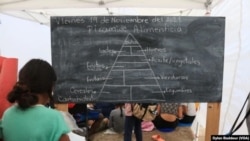 Una niña copia la pirámide alimentaria en la Escuela de Acera para Niños Solicitantes de Asilo en Reynosa, México. Foto de Dylan Baddour/VOA.