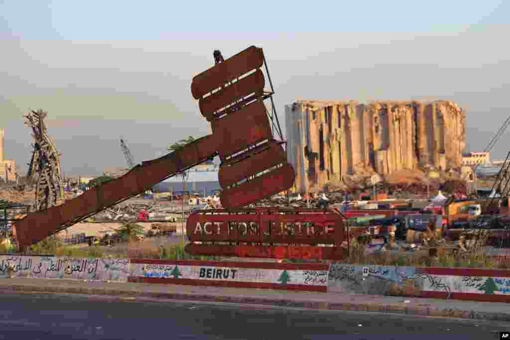 A justice symbol monument is seen in front of towering grain silos that were gutted in the massive August 2020 explosion at the port that claimed the lives of more than 200 people, in Beirut, Lebanon.