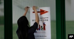 FILE - Ailu Xu, a graduate student from China, posts a sign directing Chinese students to a new student orientation meeting at the University of Texas at Dallas in Richardson, Texas, Aug. 22, 2015.