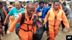 At least 50 people were killed and 59 injured in Papua Province, Indonesia, March 17, 2019. In this photo provided by National Search and Rescue Agency, the agency's personnel and police carry the body of one flood victim at Sentani, the hardest-hit district.