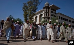 FILE-- Sami-ul-Haq, center in grey turban, a Pakistani Islamist politician and head of the Islamic seminary Darul Uloom Haqqania, is surrounded by students as he leaves after delivering a lecture at his seminary in Akora Khatak, Pakistan.